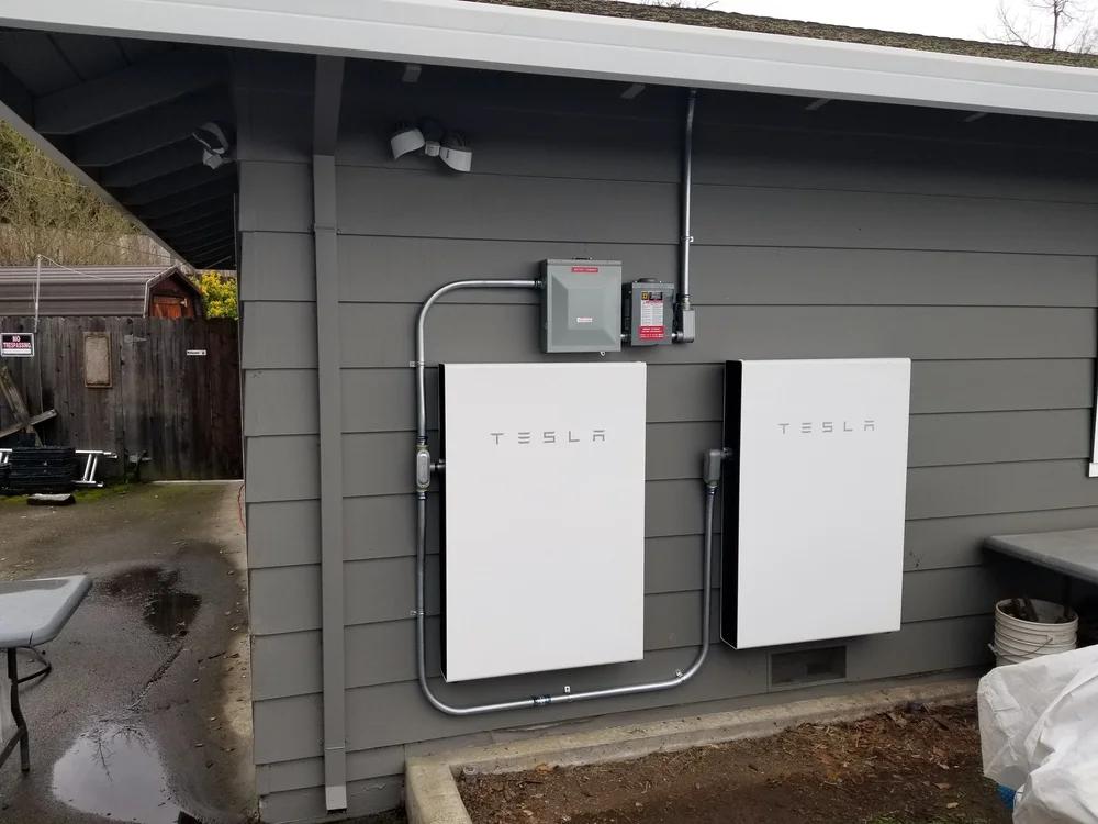 Two wall-mounted batteries on a garage wall