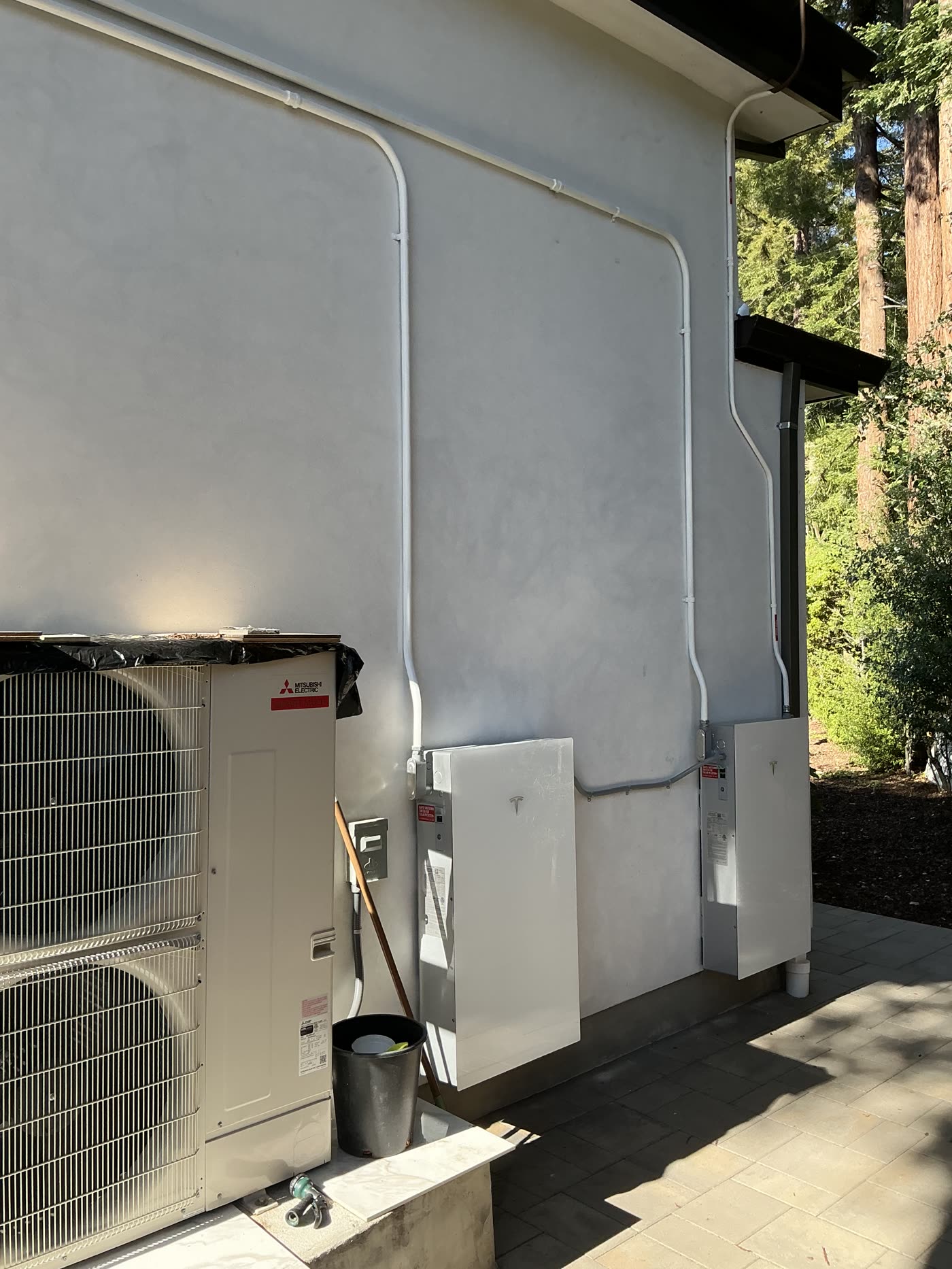 Home battery and heat pump equipment installed along an exterior wall