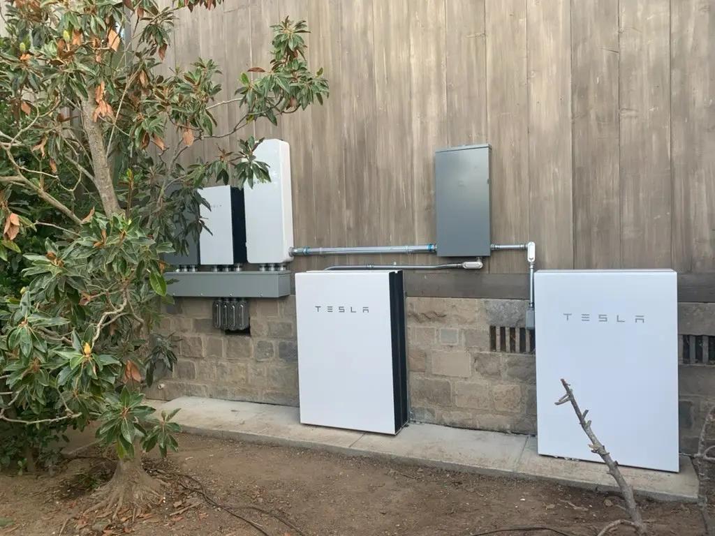 Two batteries with inverters mounted on an exterior wall